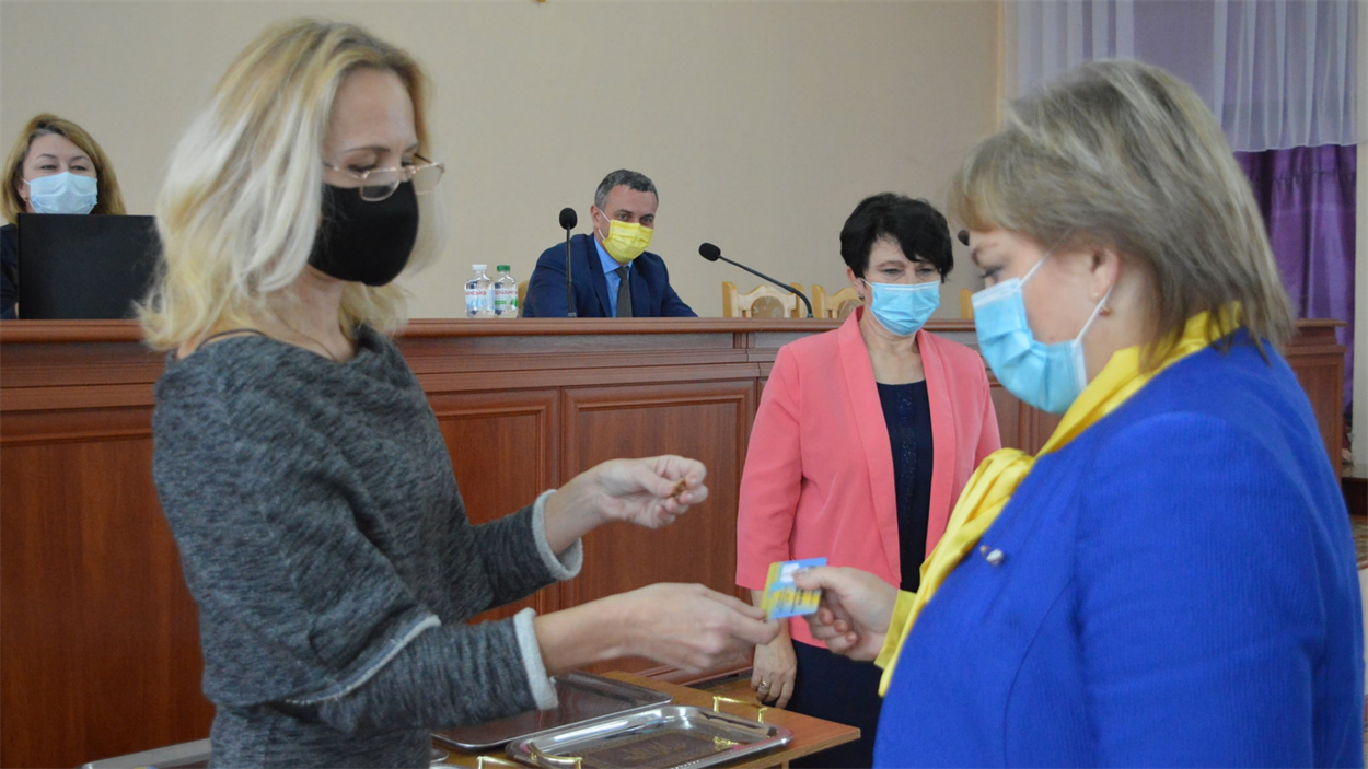 Голова Балтської ТВК Людмила Біла вручає посвідчення та депутатськиц значок новобраному депутату міської ради Оксані Тисячній